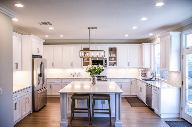 Bright modern open concept kitchen with white cabinetry, large central island, and natural light flooding the space.