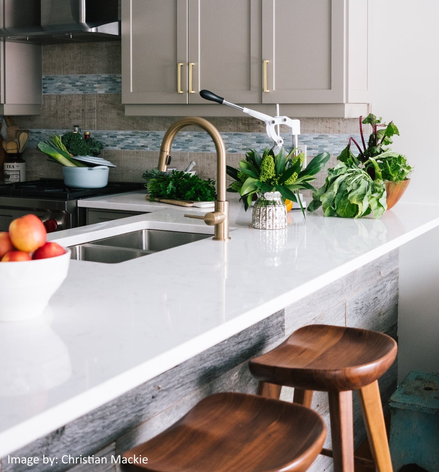 Bright kitchen interior with marble countertop, brass fixtures, and organic greenery representing natural design elements.
