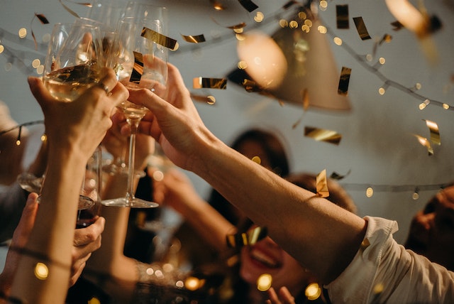 Hands clinking champagne glasses with golden confetti falling in festive New Year’s Eve celebration