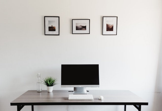 Three minimalist Nordic style framed artworks above a clean desk setup