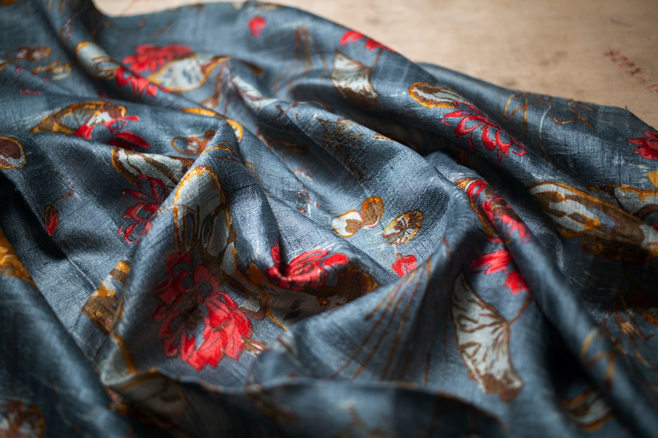 close-up of floral printed fabric with red and gold accents on blue background