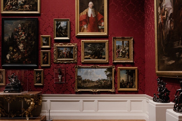 elegant art museum interior showcasing numerous framed artworks on a red wall